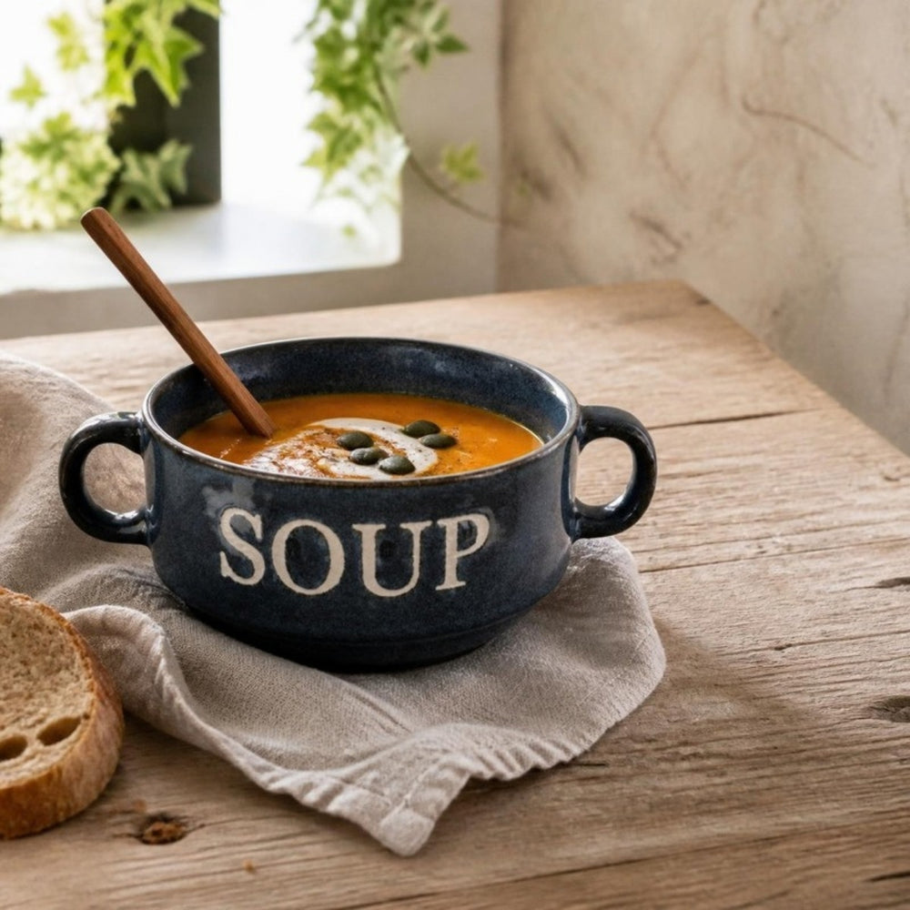 Blauwe Soup soepkom met pompoensoep en houten lepel op een linnen servet
